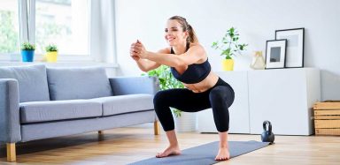 A woman squatting on a yoga mat.