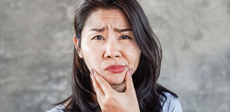 A woman making an uncomfortable face and holding her mouth.