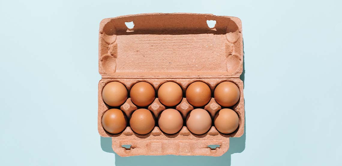 A carton of eggs against a light blue background.