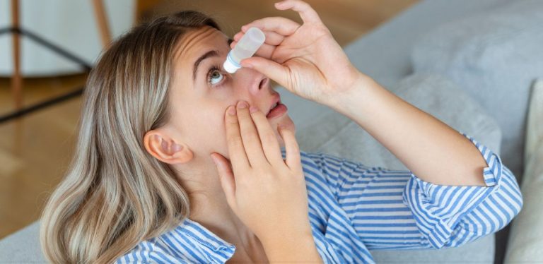 A woman putting eye drops in her eyes