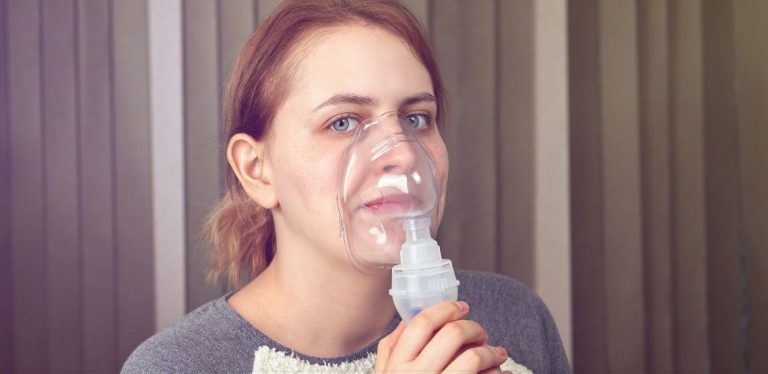 A woman holding an oxygen mask up to her face.