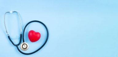 A stethoscope and red plastic heart on a blue background.